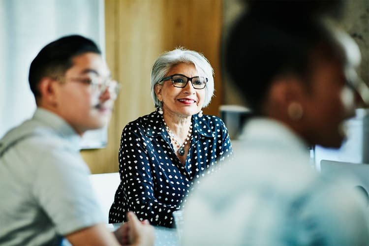 Smiling white-haired Latinx woman in a meeting